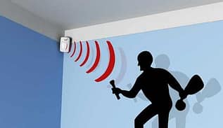 Détecteur de mouvement installé dans un angle de plafond, émettant des ondes rouges vers la silhouette d’un intrus pour indiquer la détection de mouvement.